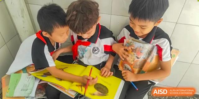 A close-up of two Shenzhen Yaohua Experimental School students collaborating on an assignment in a large yellow textbook.