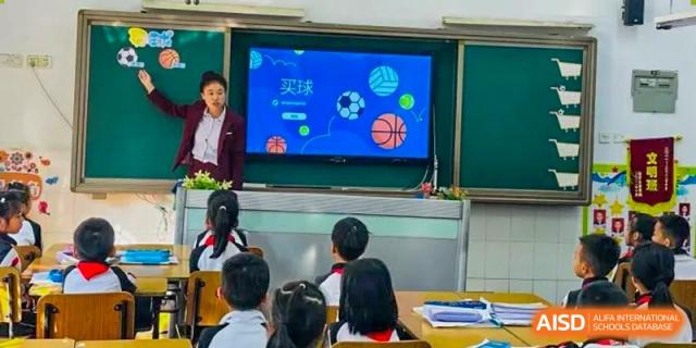 Young students from Shenzhen Yaohua Experimental School watching a presentation about sports on a large screen in their classroom.