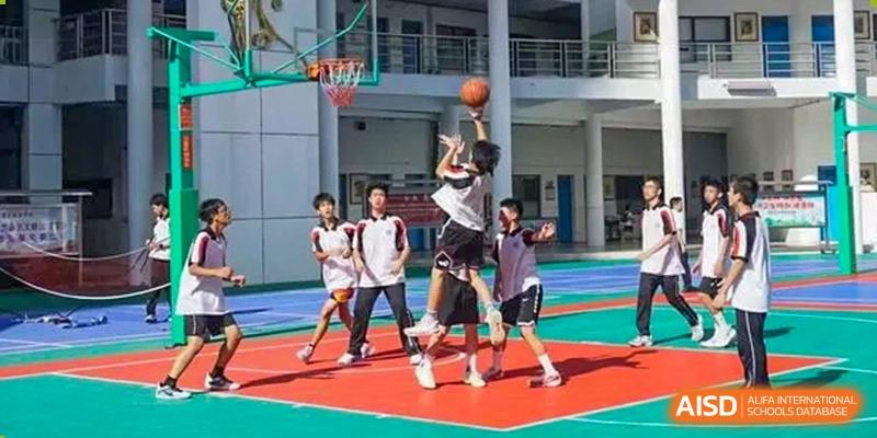 Shenzhen Yaohua Experimental School students playing basketball outdoors, with one student jumping up to shoot the ball into the hoop.