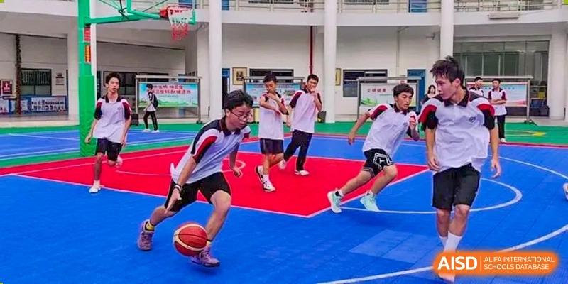Shenzhen Yaohua Experimental School students in white and red uniforms playing an intense game of floorball or indoor football on a red and blue court.