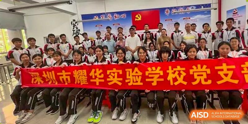 A large group of smiling Shenzhen Yaohua Experimental School students posing with a banner that features the school's name.