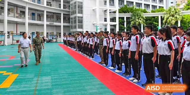 A line of male Shenzhen Yaohua Experimental School students in uniform standing at attention on a red carpet during a ceremony.