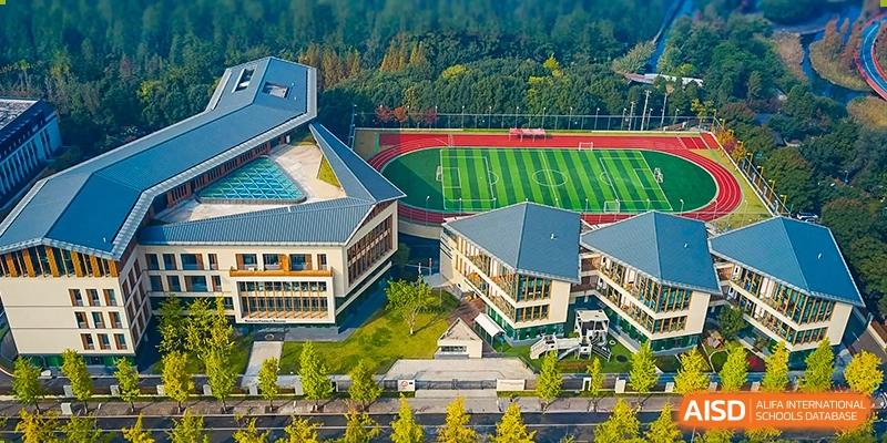 An aerial view of the campus of SPGS International School Chengdu, showcasing the sports fields, buildings, and surrounding natural landscape.