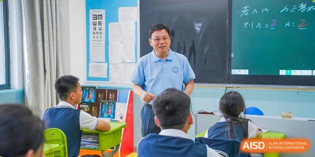 A teacher in a blue shirt helping a student at a desk at Huzhou South Taihu Bilingual School.