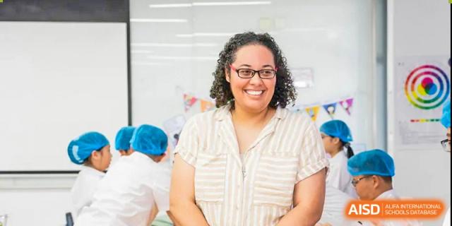 A smiling female teacher with glasses at Huzhou South Taihu Bilingual School.