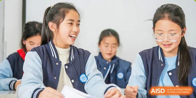 Two smiling students sitting together at Huzhou South Taihu Bilingual School.