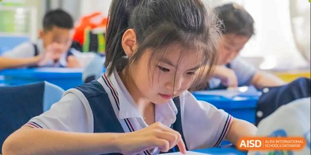 A student writing in a notebook at her desk at Huzhou South Taihu Bilingual School.