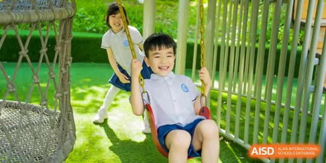 A young student smiling on a swing on a playground at Huzhou South Taihu Bilingual School.