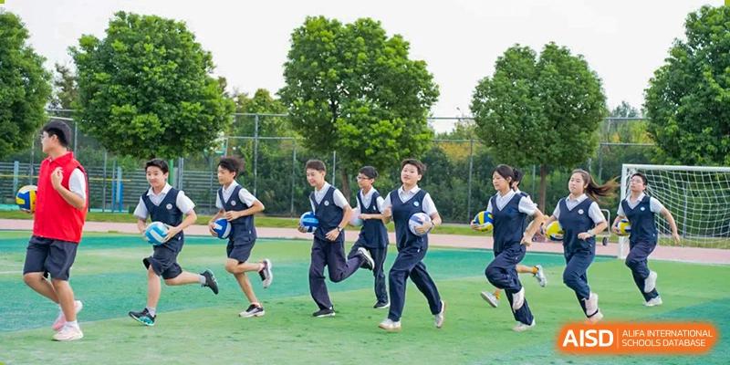 A group of students running on a grassy field during a sports activity at Huzhou South Taihu Bilingual School.