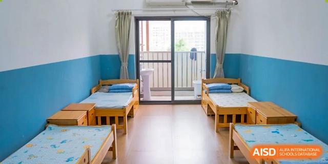 A school dormitory room with two single beds and a large window at Huzhou South Taihu Bilingual School.
