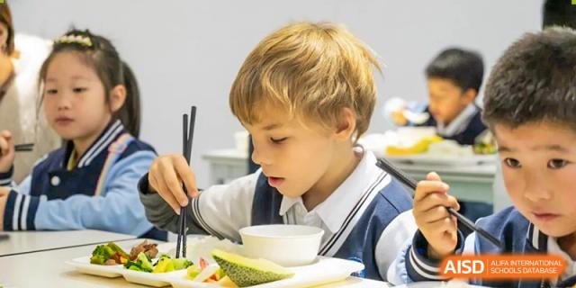 A young student eating a meal in the cafeteria at Huzhou South Taihu Bilingual School.