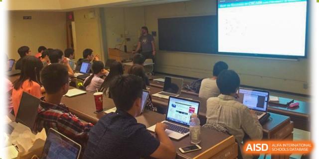 A student from The First High School of Changsha, Hunan working on a laptop in a classroom or lab setting, seen from behind.