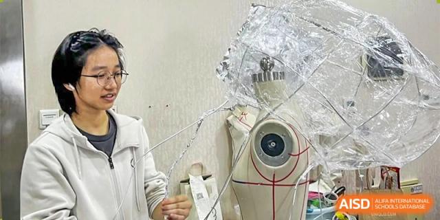 A student from The First High School of Changsha, Hunan working on a science or art installation, manipulating wire or foil around a mannequin torso.