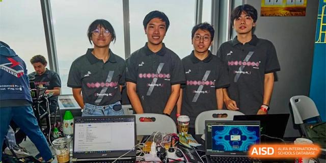 A group of three students from The First High School of Changsha, Hunan standing proudly with their robotics or electronics project on a table in front of them.
