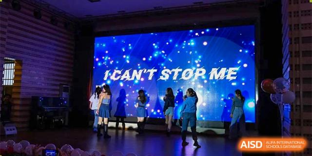 Students from The First High School of Changsha, Hunan performing a dance on a brightly lit stage with a large screen displaying the text 'I CAN'T STOP ME'.