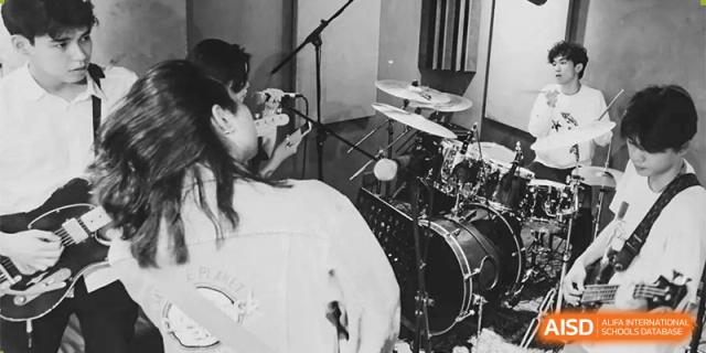 A student from The First High School of Changsha, Hunan playing a drum set, captured in a black and white close-up.