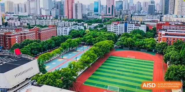 Students from The First High School of Changsha, Hunan lined up on a green sports field, possibly for military training or a school assembly, with an instructor facing them.