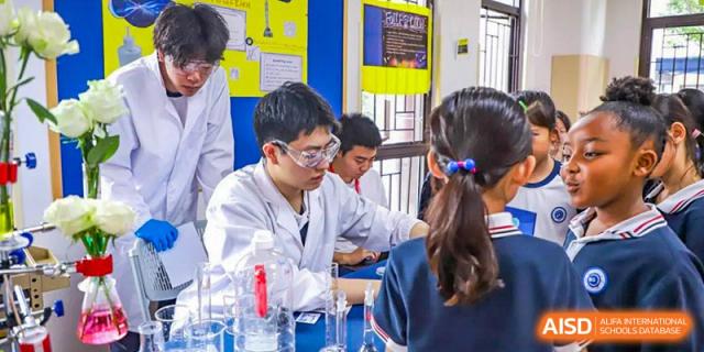 BASIS International School Nanjing students in lab coats and safety glasses working on a science experiment.