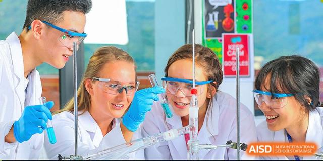 BASIS International School Nanjing students in lab coats and safety goggles working on a science experiment.