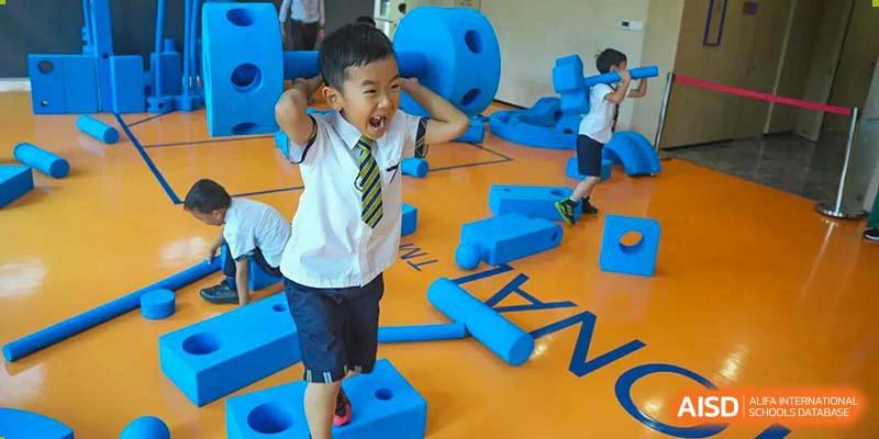 A young BASIS International School Nanjing student with an expressive face in a play area with large blue blocks.