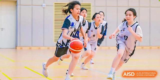 BASIS International School Nanjing students playing basketball in an indoor gymnasium.