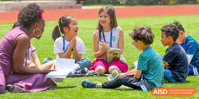 A young BASIS International School Nanjing student sitting on the grass and reading a book.