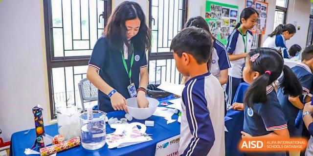 An adult helping BASIS International School Nanjing students with a project at a table.