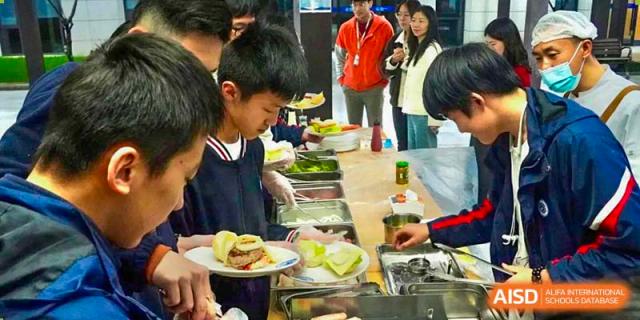 A young BASIS International School Nanjing student is serving themselves food from a buffet.