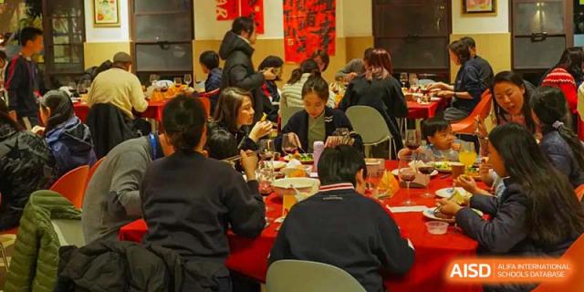 BASIS International School Nanjing students and adults are eating together in a cafeteria.