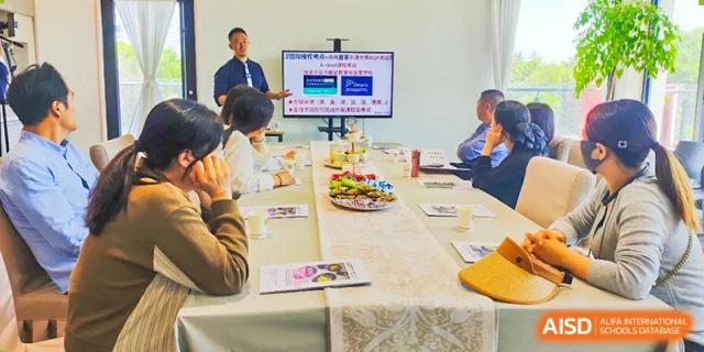 A meeting or academic discussion at Vindu-Charlie Lakefield College with students and staff seated around a table and viewing content on a large screen.