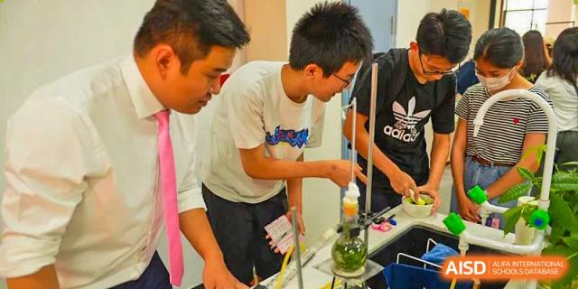 Two Vindu-Charlie Lakefield College students working together on a practical science experiment, pouring a liquid into a funnel.