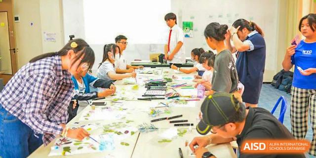 A group of students works collaboratively on an art or craft project spread across a large table at Vindu-Charlie Lakefield College.
