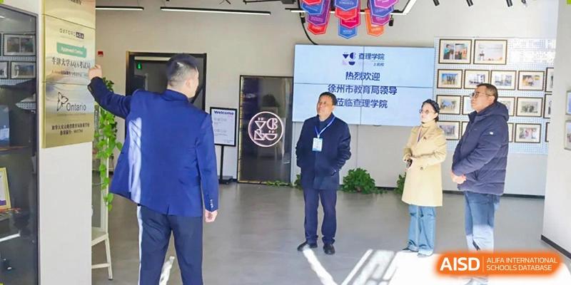 A male staff member or speaker from Vindu-Charlie Lakefield College standing on a stage in front of a screen displaying text in both English and Chinese.