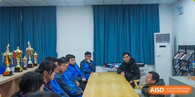 Students from The High School Attached to Hunan Normal University seated around a large table, participating in a group discussion or small seminar.