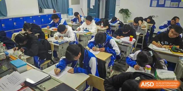 Students from The High School Attached to Hunan Normal University focused on writing and working at their desks during a class period.