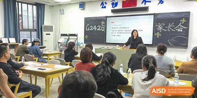 A large class from The High School Attached to Hunan Normal University being led by a teacher at the front, with students seated and facing the instructor.
