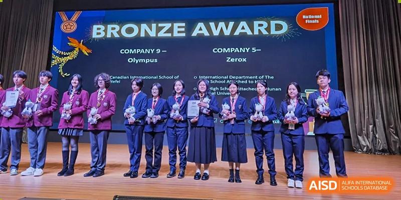 Students from The High School Attached to Hunan Normal University on stage receiving a Bronze Award for "Company 5 - Olympus" and "Company 5 - Zerox."