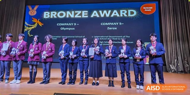 Students from The High School Attached to Hunan Normal University on stage receiving a Bronze Award for "Company 5 - Olympus" and "Company 5 - Zerox."