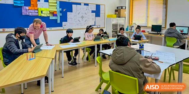 Wenzhou Union International School (WUIS) students seated at desks, engaged in a lesson in a bright classroom with whiteboards.