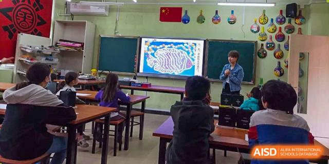 Wenzhou Union International School (WUIS) students seated at desks, facing a large screen displaying an image of the human body for a science lesson.