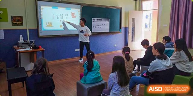 A teacher at Wenzhou Union International School (WUIS) instructing a small group of students seated on the floor in front of a smart board.