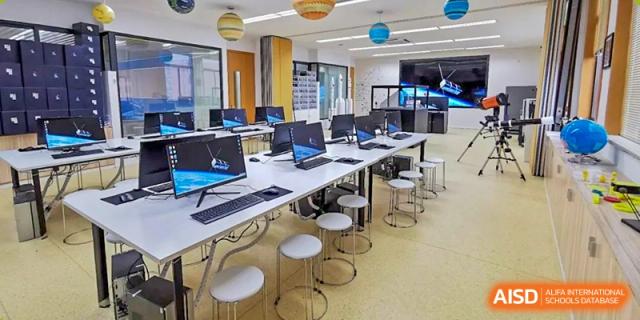 A clean, modern Wenzhou Union International School (WUIS) computer lab with rows of desktops and round white stools.
