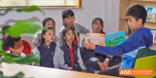 A small group of Wenzhou Union International School (WUIS) students seated and intently listening to a book being read aloud.