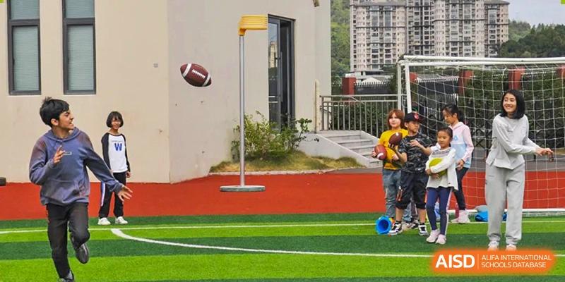 A korfball post with a floating American football over a brightly colored green and red sports field at Wenzhou Union International School (WUIS).