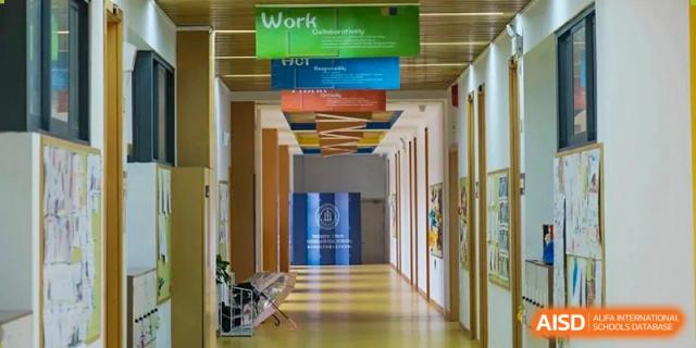 A view of a modern, well-lit hallway at Wenzhou Union International School (WUIS) with colorful banners hanging from the ceiling.