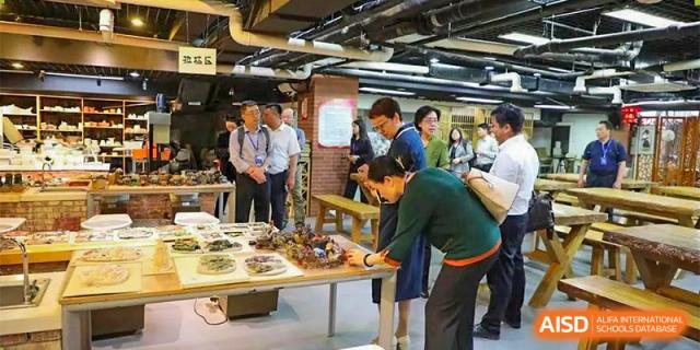 CNUH-GA Curriculum Partnership Program Attendees examine items displayed on a table at an event or exhibition, possibly an indoor laboratory or workshop setting.