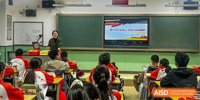 CNUH-GA Curriculum Partnership Program Students sitting in a classroom, facing a green chalkboard and a large screen displaying what appears to be a presentation or informational slide in Chinese.