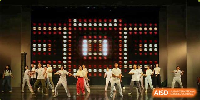 A group of students from the CNUH-GA Curriculum Partnership Program performing a dance in front of a stage with a bright, dynamic LED background.