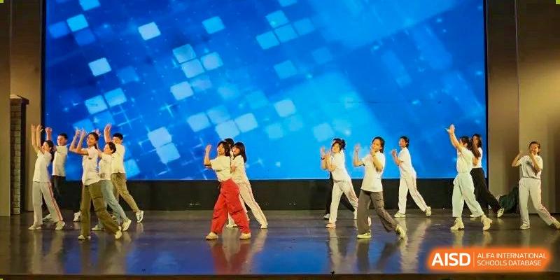 Female students from the CNUH-GA Curriculum Partnership Program performing a choreographed dance routine on a dark stage.