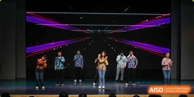 A student from the CNUH-GA Curriculum Partnership Program performing a solo vocal or musical number on a dark stage with a dynamic light display.